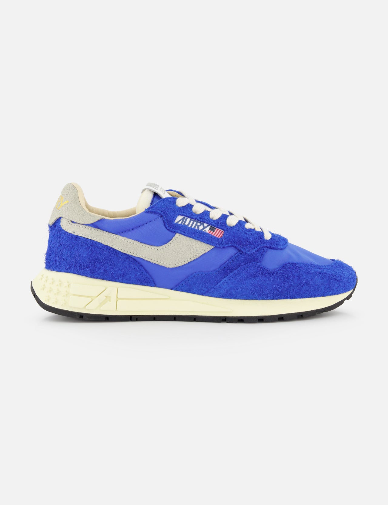 The AUTRY Reelwind Low Running Sneakers feature blue and beige suede and mesh, white and blue laces, a beige logo, and a cream sole—ideal for an active lifestyle—displayed in side profile against a plain white background.