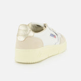 Introducing the Medalist Low Gold Heel Sneaker by AUTRY—a white leather sneaker enhanced with a beige accent, distinctive gold heel, and cream platform sole. Seen from a back side angle, it proudly features AUTRY branding on both the heel and side, offering an elevated take on iconic 1980s tennis shoe style.