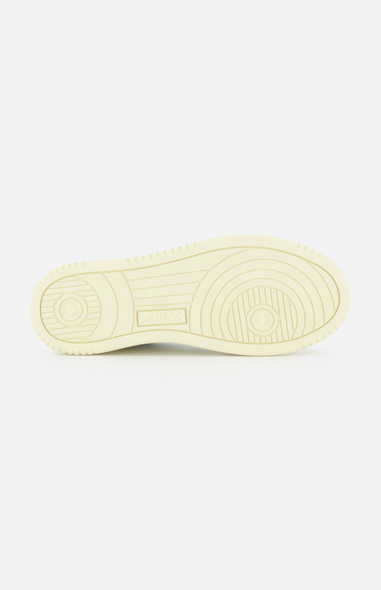 The image shows the sole of the AUTRY Medalist Low Gold Heel Sneaker, featuring circular and linear tread patterns reminiscent of classic 1980s tennis shoes, with a small rectangular section in the center displaying text.