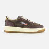 Introducing the AUTRY Medalist Low Suede Sneaker with Croco-effect: a low-top sneaker crafted from rich dark chocolate brown suede with distinctive croco-effect detailing. It features crisp white laces, a gum sole, and is finished with a small American flag logo on the side that reads AUTRY. Inspired by classic 1980s tennis shoes, this design effortlessly blends vintage appeal with contemporary style.