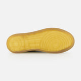 Bottom view of the AUTRY Medalist Low Suede Sneaker with Croco-effect, featuring a yellow rubber sole with textured circular grip patterns reminiscent of 1980s tennis shoes, photographed against a white background.