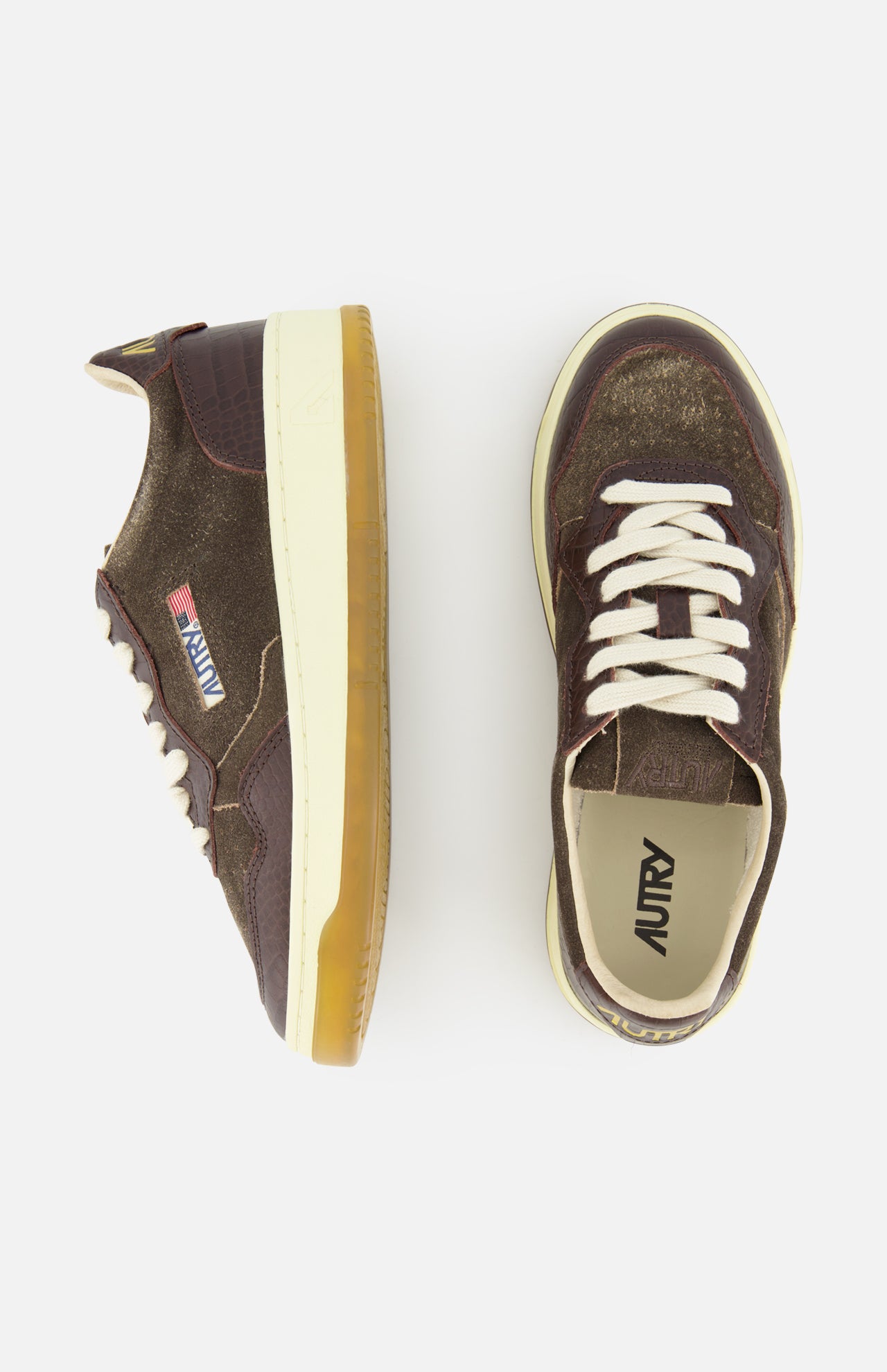 A pair of AUTRY Medalist Low Suede Sneakers with Croco-effect in dark chocolate brown, featuring white laces and gum soles, seen from the side and top against a white background. Inspired by classic 1980s tennis shoes, these sneakers combine vintage charm with contemporary design details.