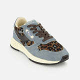 The AUTRY Reelwind Low Pony Hair Sneaker showcases blue and brown panels, leopard print accents, brown laces, a cream-colored midsole, and a black outsole—delivering stylish versatility for an active lifestyle—all displayed against a white background.