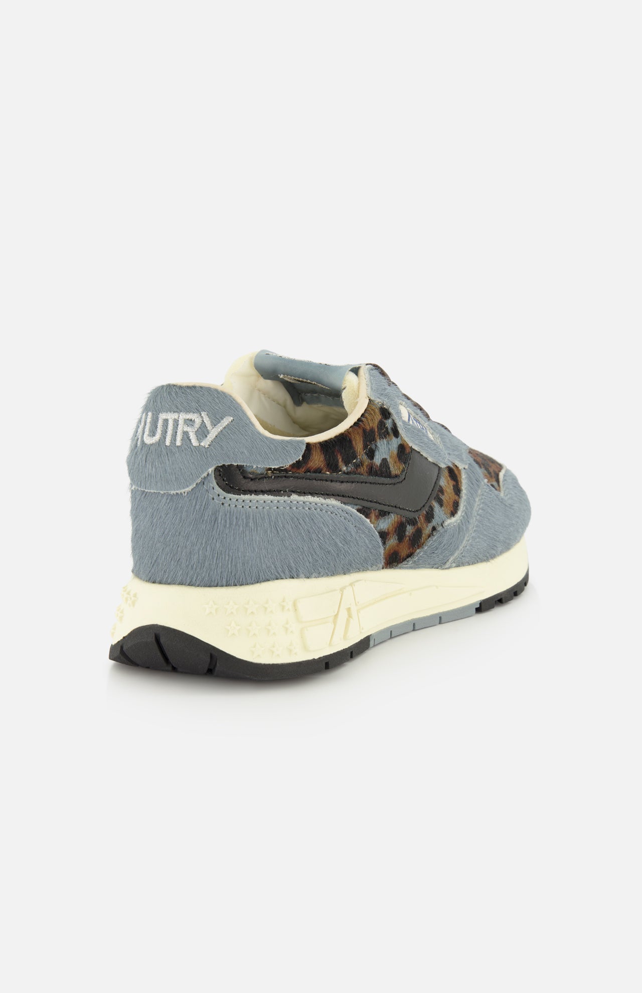 Introducing the AUTRY Reelwind Low Pony Hair Sneaker—a stylish low-top designed for active lifestyles, featuring gray suede and leopard print accents, a cream sole, and AUTRY branding on the heel. Shown from a back side angle against a white background.