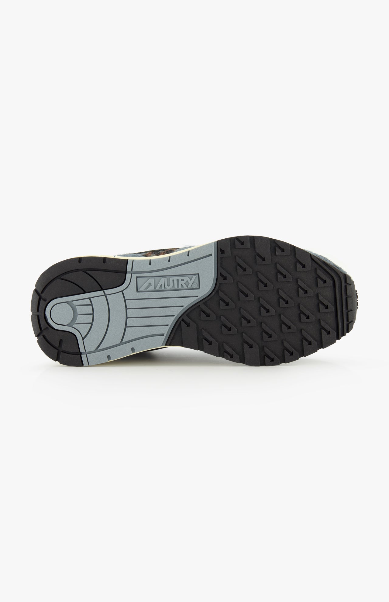 The image displays the black and gray sole of the AUTRY Reelwind Low Pony Hair Sneaker, viewed from beneath, with the brand name AUTRY embossed at the center. The tread features triangular patterns designed for grip, making it ideal for an active lifestyle.