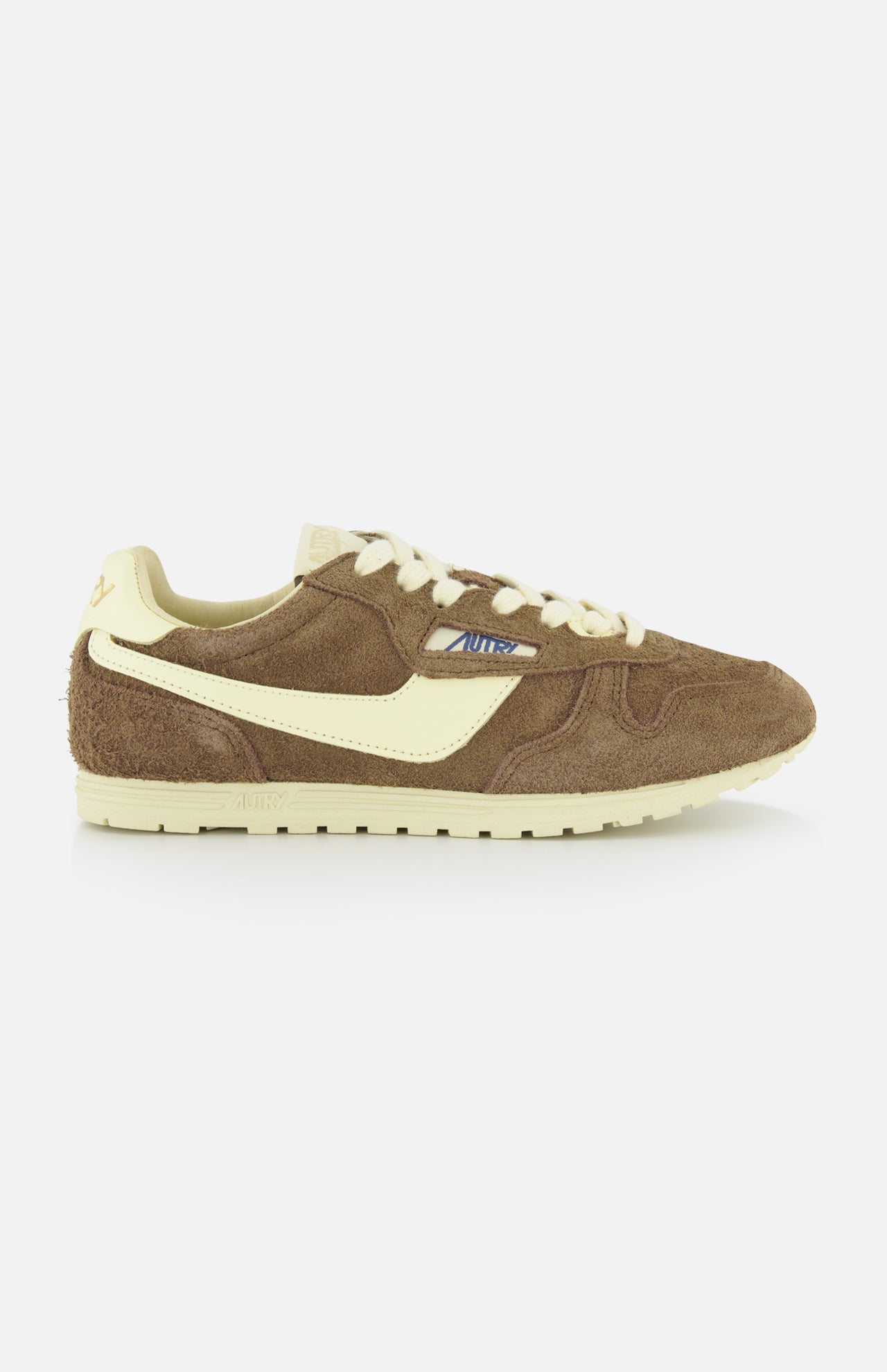 The Autry Windspin Low Brushed Suede Sneaker features a dark brown suede upper, cream accents, laces, and side stripe for a vintage 60s look, shown against a white background.