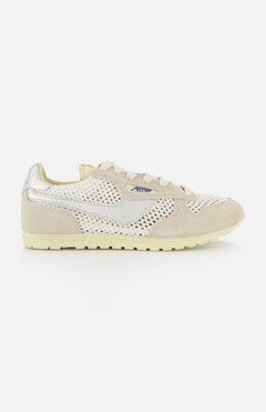 The AUTRY Windspin Low Knit Sneaker features beige mesh, suede overlays, a cream sole, a subtle white swoosh on the side, and a small blue AW logo near the laces for classic vintage style.