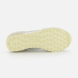 The image shows the underside of the AUTRY Windspin Low Knit Sneaker, featuring a light yellow textured rubber sole with patterned tread for grip and AUTRY embossed at the center, reflecting classic 60s sneaker style.