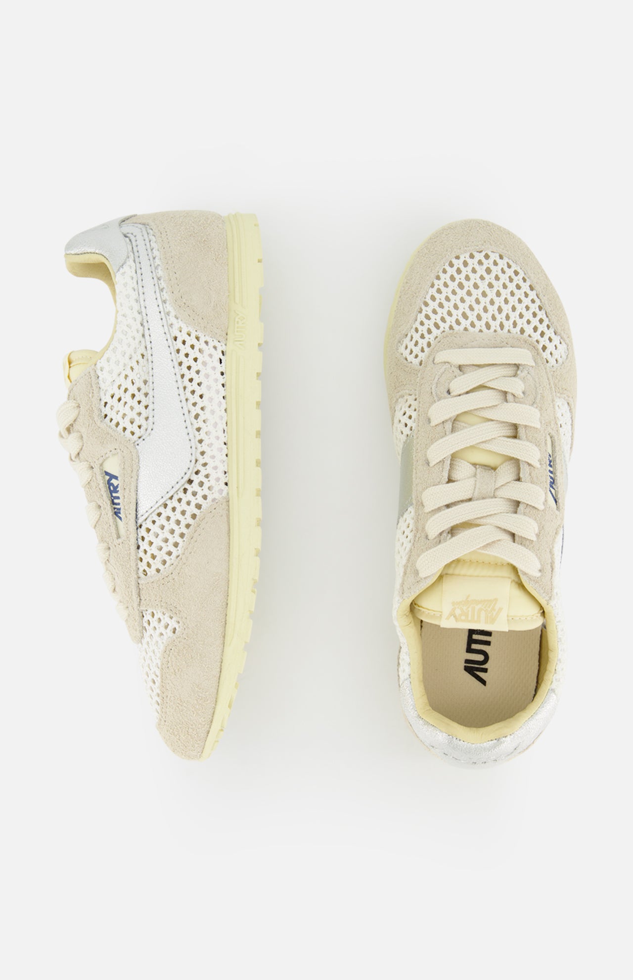 Two cream and beige AUTRY Windspin Low Knit Sneakers with mesh panels, suede accents, laces, textured soles, and blue branding are displayed on a white background—one from the side, the other from above.