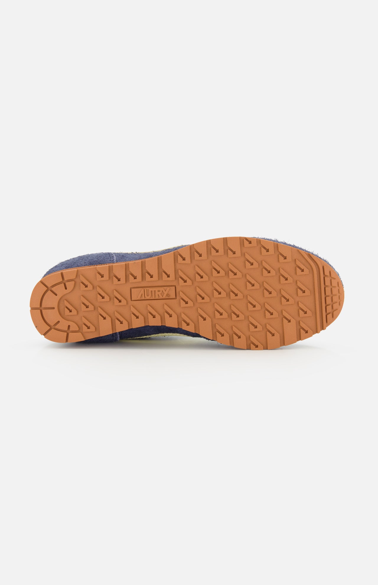 A close-up of the Windspin Low Suede Sneaker’s sole by AUTRY, featuring a brown rubber tread pattern with AUTRY embossed at the center, displayed against a white background—perfectly embodying the vintage charm and classic 60s-inspired sneaker aesthetic.