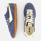 The AUTRY Windspin Low Suede Sneaker is showcased from the side and top against a white background, featuring a blue and cream retro-inspired design with gum soles. Its dark blue suede accents capture the timeless appeal of classic 60s-style sneakers, embodying vintage charm.