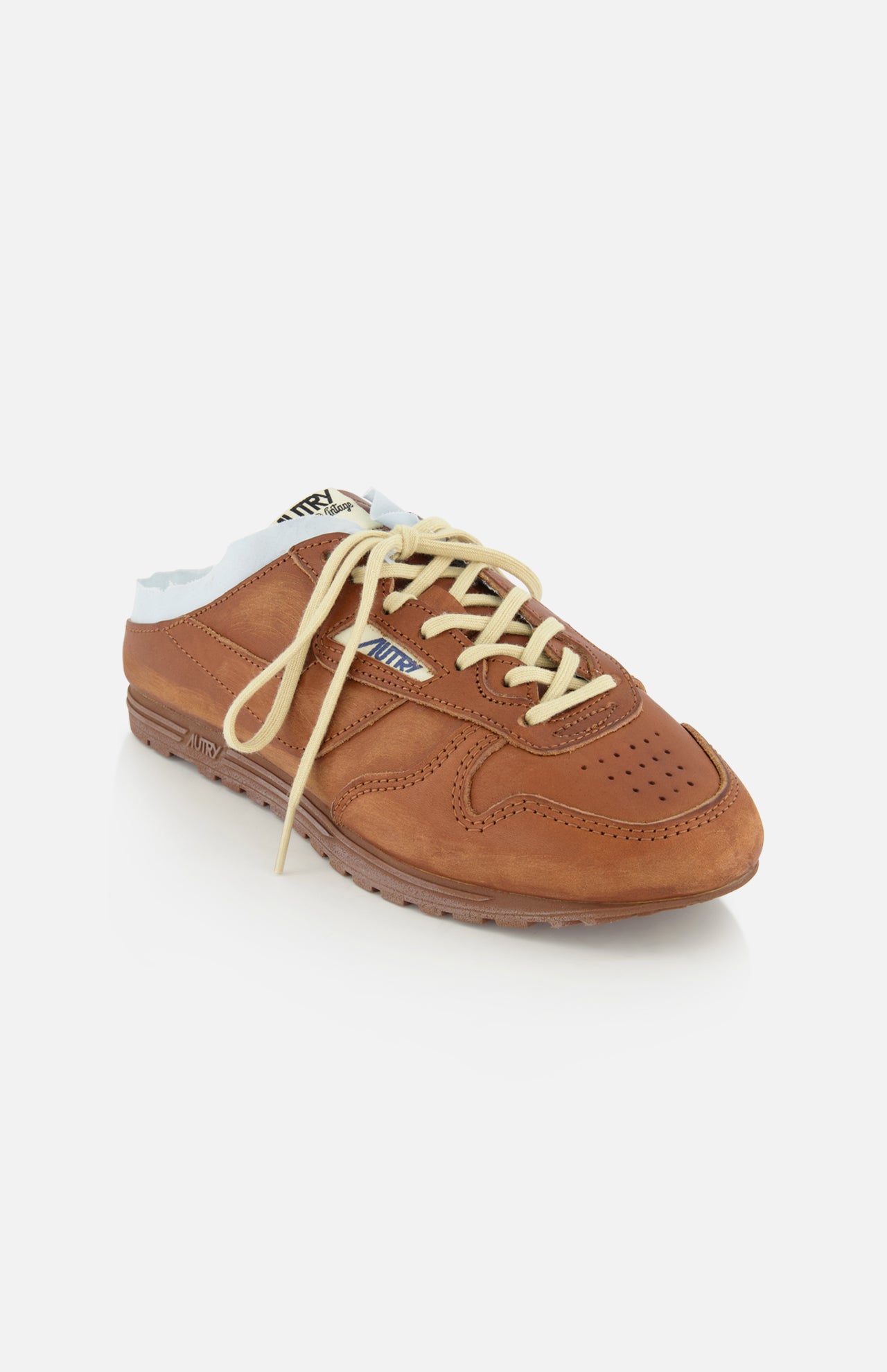 The AUTRY Windspin Leather Mule Sneaker features brown leather, cream laces, light blue lining, and a perforated toe for vintage style, showcased on a white background.