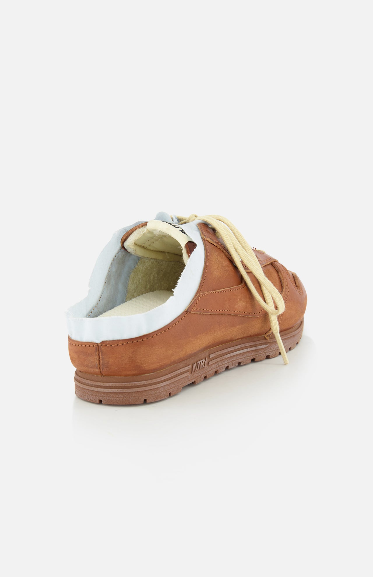 The AUTRY Windspin Leather Mule Sneaker in brown features beige laces and exposed white lining, shown from the back left on a plain white background, blending slip-on ease with vintage flair.