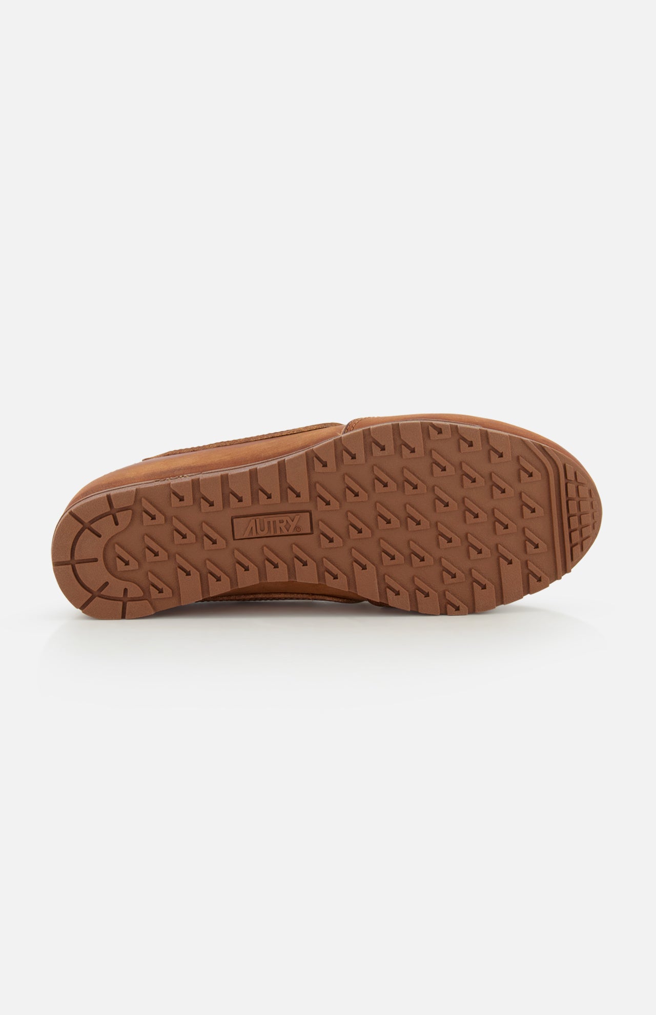 The image displays the brown rubber sole of the AUTRY Windspin Leather Mule Sneaker facing up, with a zigzag tread and central AUTRY branding. The plain white background highlights its vintage appeal.