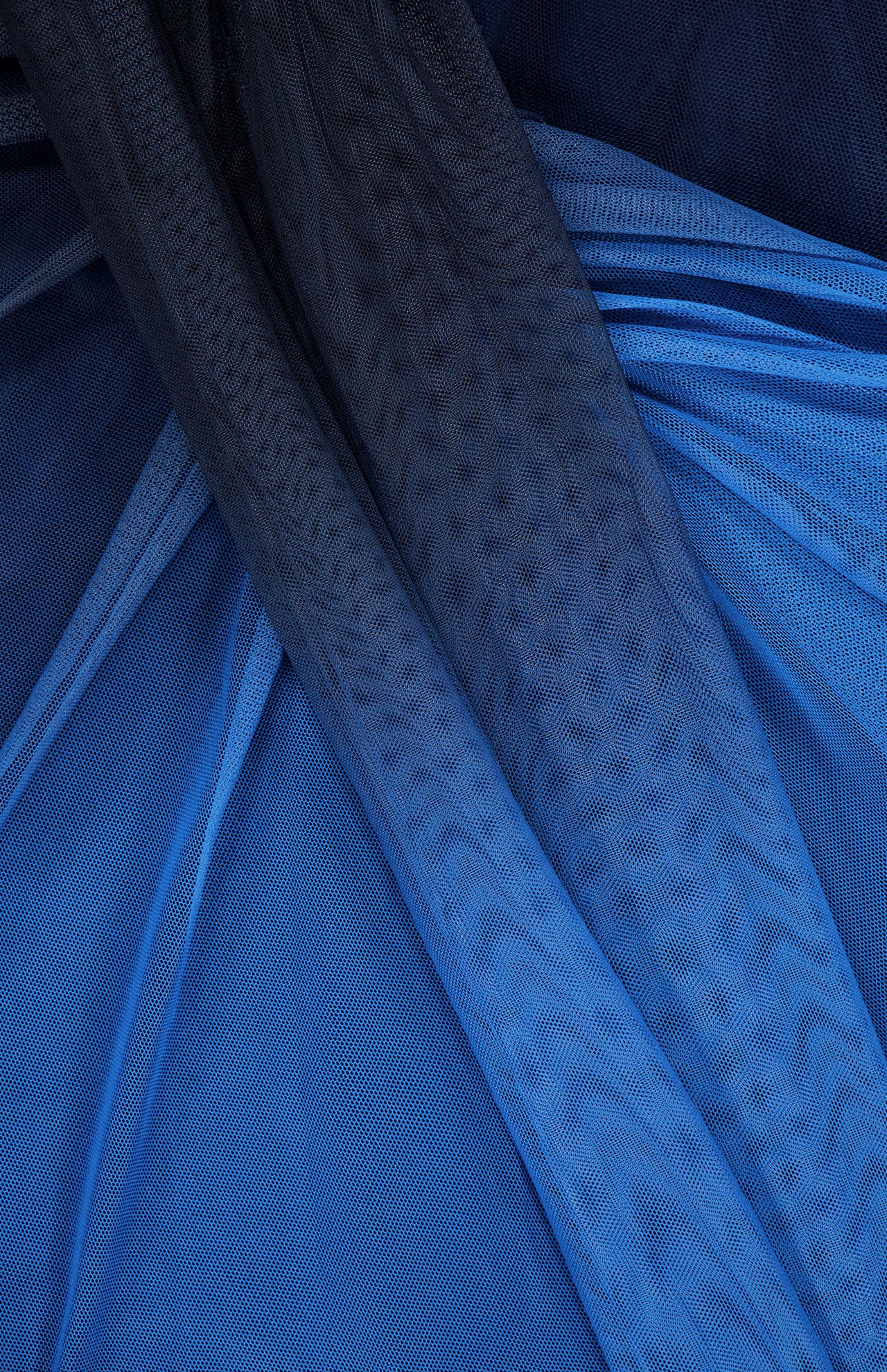 Close-up of layered blue mesh fabric in varying shades and textures from the Lena Strapless Maxi Dress by BAOBAB, featuring draped folds that create cascading details and a wavy, patterned look.
