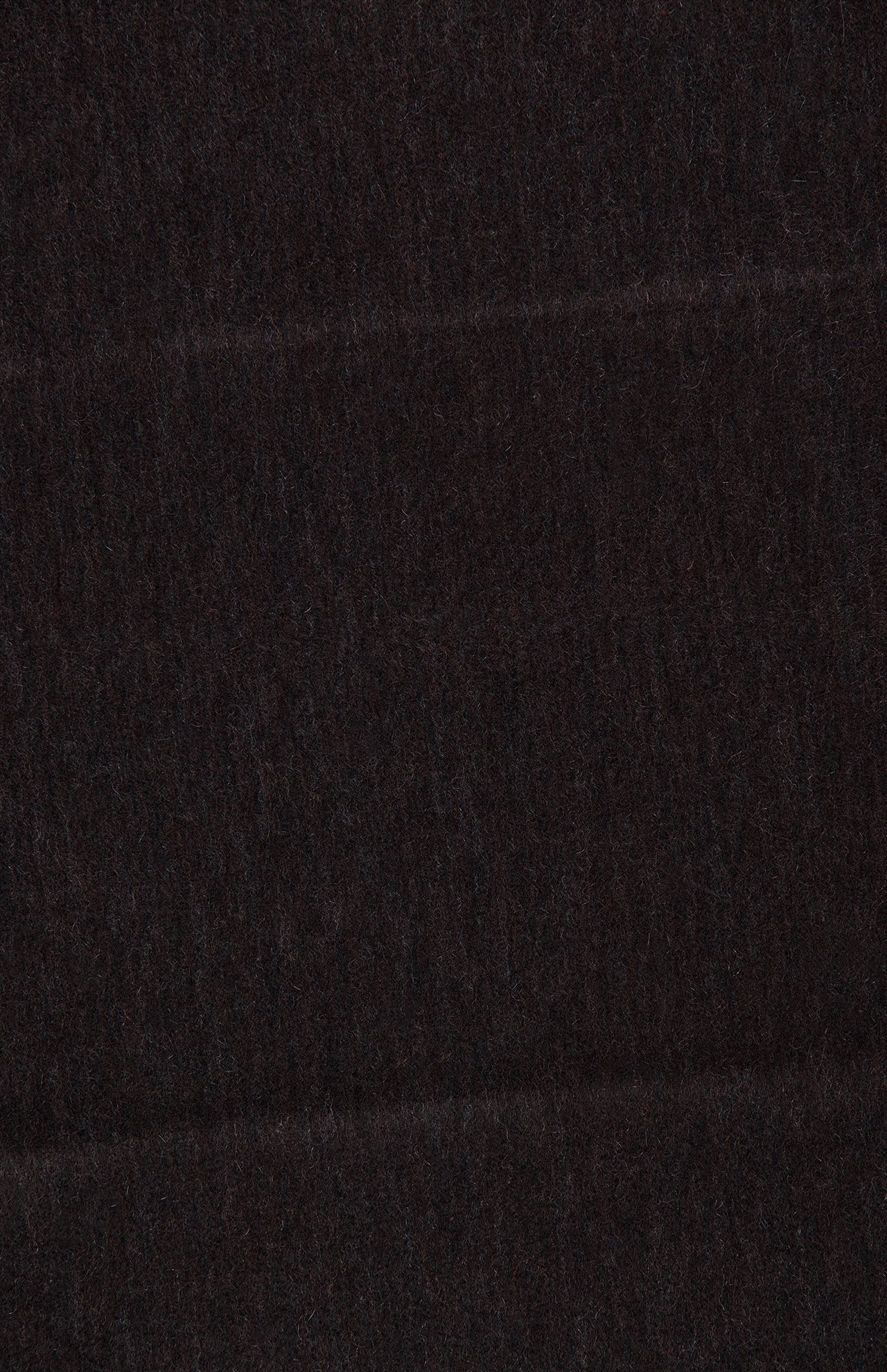 A close-up of the BEGG & CO Arran Reversible Scarf showcases its dark, textured cashmere with subtle horizontal lines and a gently fuzzy surface. The deep brown or black color accentuates the luxurious quality of this reversible accessory, expertly crafted in Scotland.