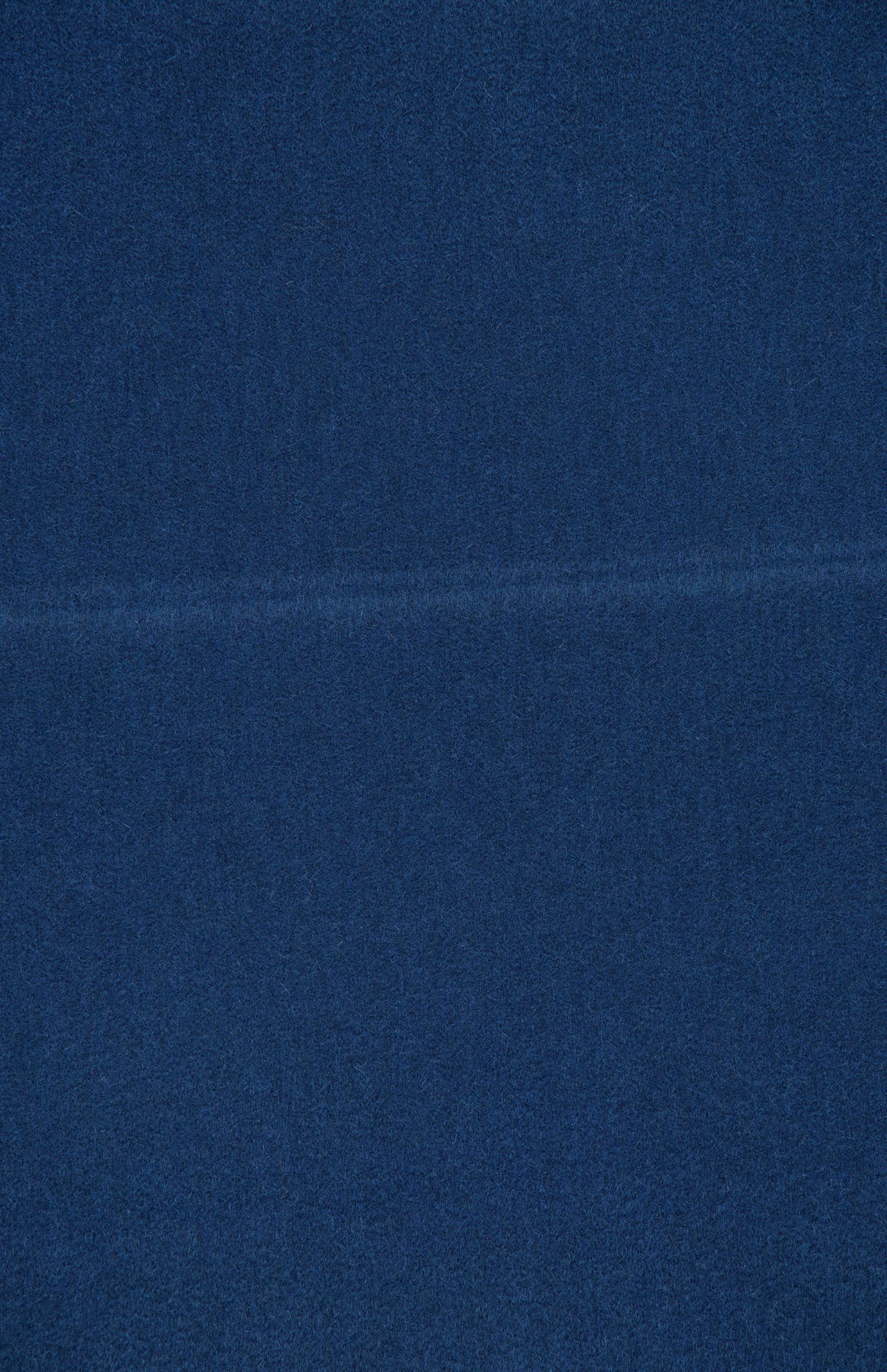 A close-up of a textured blue surface with a faint horizontal line running across the middle, reminiscent of the subtle weave found in the Arran Solid Scarf by BEGG & CO.