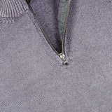 Close-up of the BELSTAFF Garment Dye Aspect Quarter Zip Sweater in light purple wool, featuring a partially unzipped metal quarter zip and ribbed collar with a small black tag visible inside the neckline. Made from responsibly-sourced wool for enhanced comfort and sustainability.