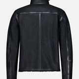 The BELSTAFF Highland Shearling Jacket in black is shown from the back, highlighting a straight center seam, visible side seams, and plush shearling lining at the hem, cuffs, and collar. Inspired by classic British heritage style, it is set against a light gray background.