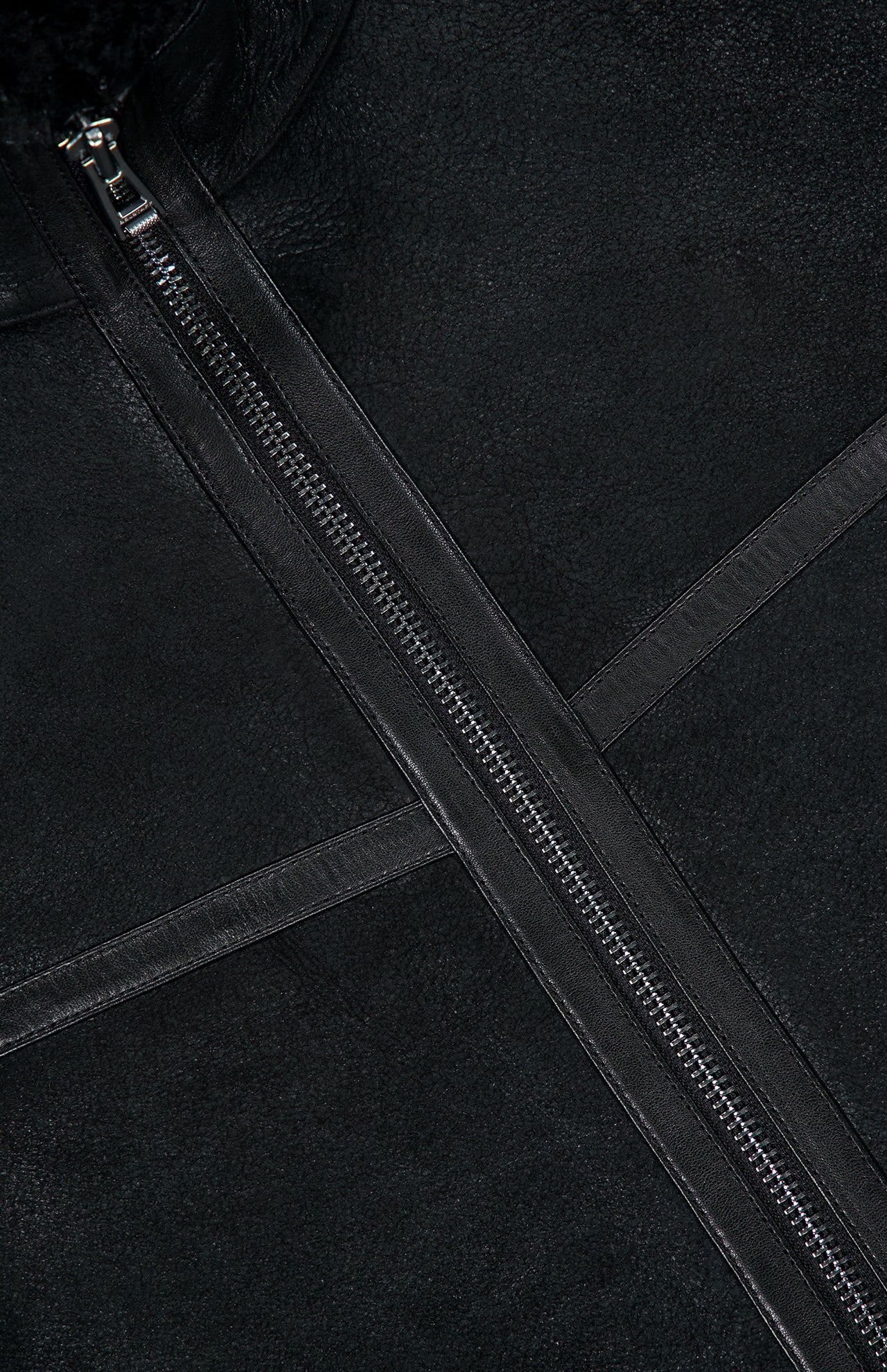 Close-up of the Highland Shearling Jacket by BELSTAFF in black leather, featuring two intersecting leather strips and a visible silver zipper, showcasing classic British heritage design elements.