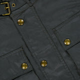 Close-up of the BELSTAFF Racemaster Waxed Cotton Jacket in dark green, featuring brass snap buttons, two flap pockets, and a buckle detail near the collar, highlighting its iconic style.