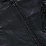 Close-up of the BELSTAFF V Racer Jacket in black leather, featuring a snap button at the collar, two parallel zippers, and visible pocket stitching that highlights the supple leather texture and minimalist design details.