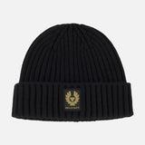 The BELSTAFF Watch Beanie Hat is a black ribbed knit wool beanie with a folded brim, accented by a rectangular black and gold BELSTAFF logo patch on the front.