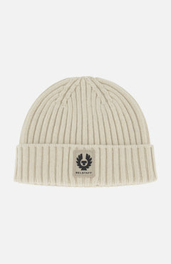 The BELSTAFF Watch Beanie Hat is a cream-colored, ribbed knit lambswool beanie with a folded cuff and a rectangular Belstaff logo patch on the front—a must-have for your cold-weather accessory lineup.