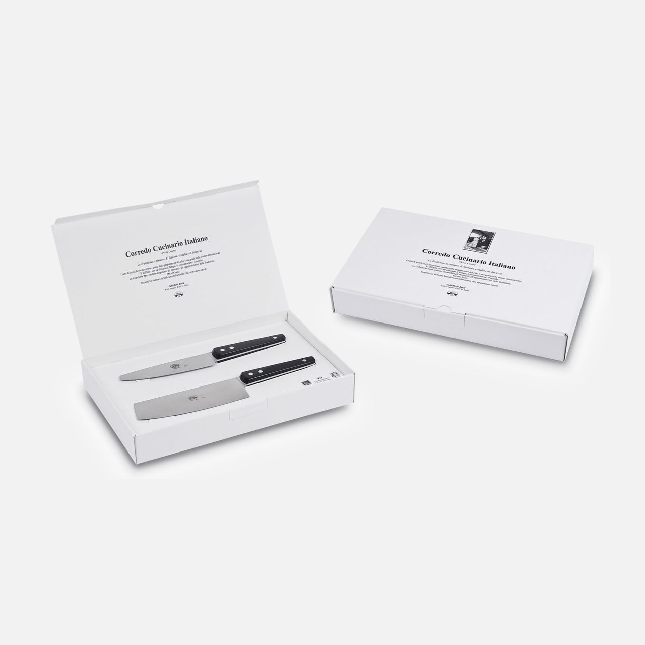 Two white boxes—one open, one closed—contain the Berti Cutlery Kitchen Knife Kit (Set of 2) with black handles. The open box displays the knives in slots, with master knife makers' text printed inside the lid.