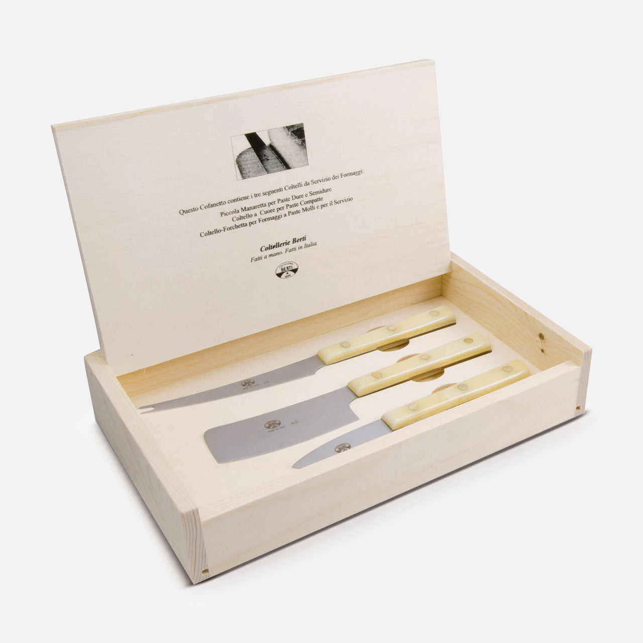A wooden gift box from Berti Cutlery with its lid open reveals three La Ceremony Dei Formaggi cheese knives with light handles arranged inside; the lid’s interior features printed text and a small image.