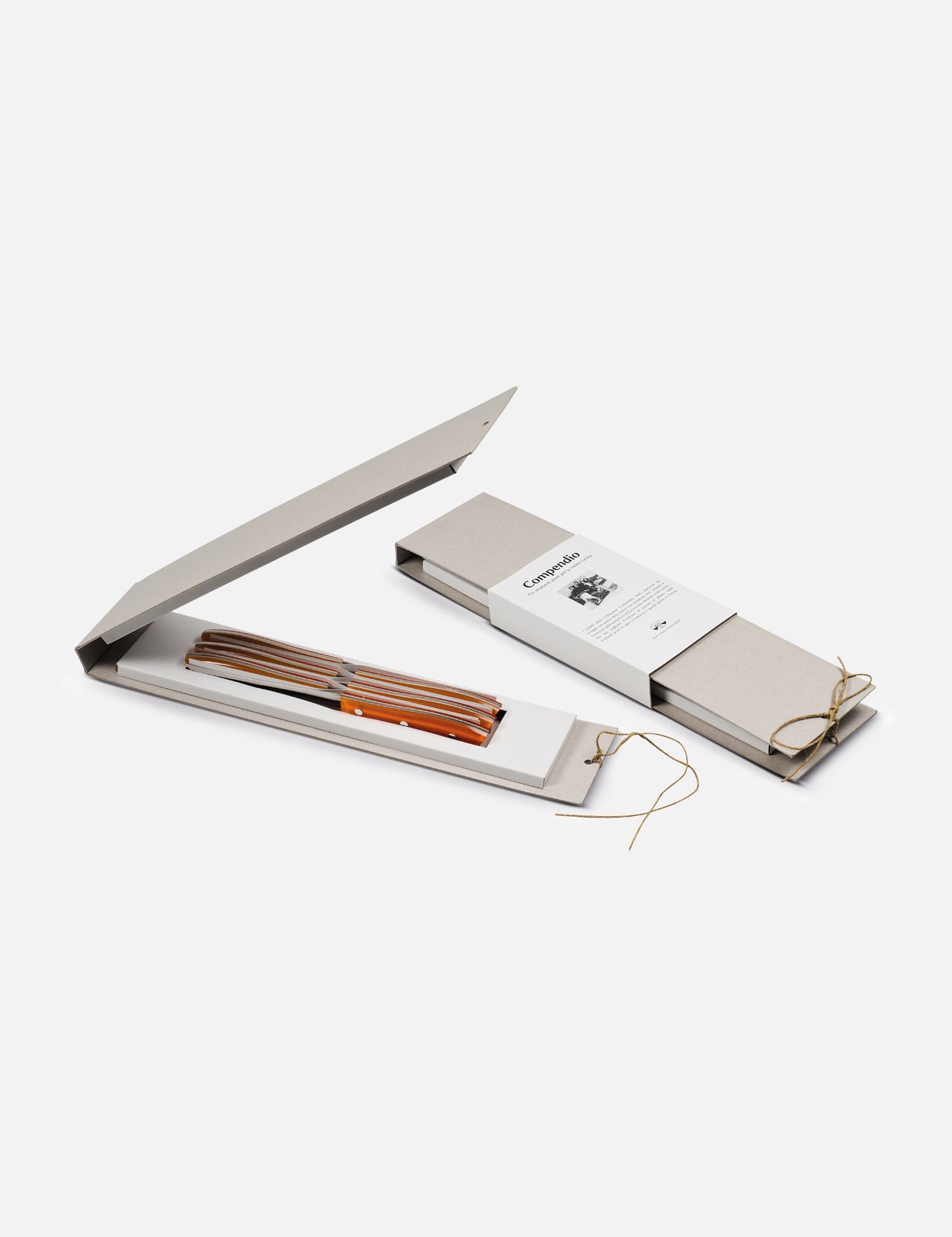 Two slim, beige Berti Cutlery boxes with string closures are shown. One is closed with a booklet on top; the other is open, displaying the Table Knife “Compendium” 6-piece set featuring elegant orange and brown striped handles.