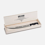 The Hussar on the Roof Sabrage Saber by Berti Cutlery features a decorative handmade knife with a black handle and engraved blade, elegantly presented in an open cream-colored box with text inside the lid—crafted in Italy.