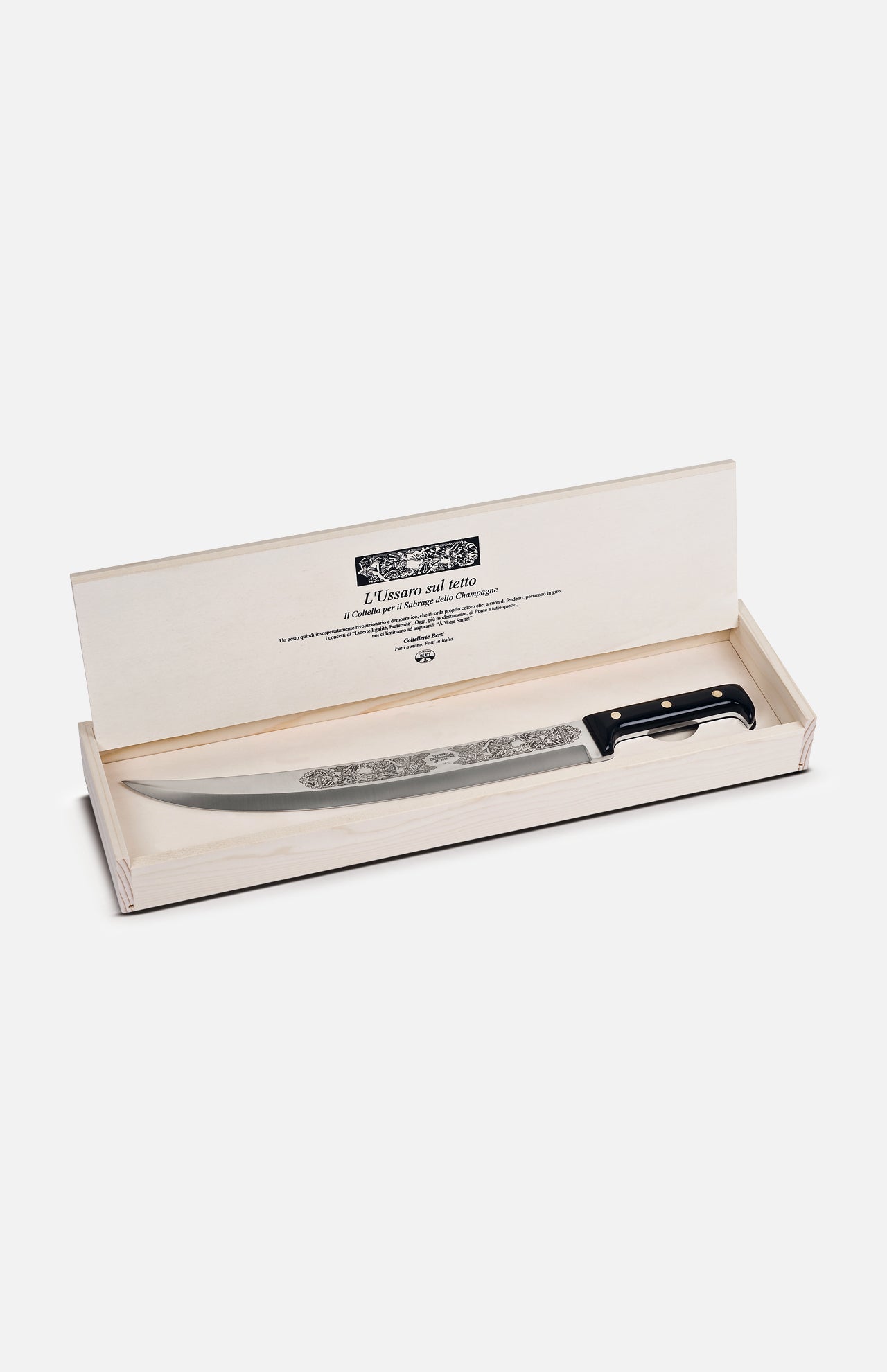 The Hussar on the Roof Sabrage Saber by Berti Cutlery features a decorative handmade knife with a black handle and engraved blade, elegantly presented in an open cream-colored box with text inside the lid—crafted in Italy.