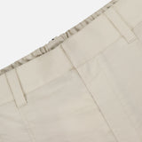 Close-up of the waistband and upper section of BRUNELLO CUCINELLI Cotton Poplin Deep Pleat A-Line Pant in beige, featuring belt loops and an elasticated waistband, shown against a plain white background.