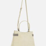 The Medium Soft Velour Essence Bag by BRUNELLO CUCINELLI features beige suede, two short handles, an adjustable shoulder strap, and gray-edged handles that highlight its minimalist design and structured shape against a white background.