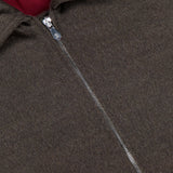 Close-up of the BRUNELLO CUCINELLI Wool Bomber Jacket in dark brown virgin wool, showcasing a prominent metal zipper, red inner lining, and a white BRUNELLO CUCINELLI label sewn near the collar.
