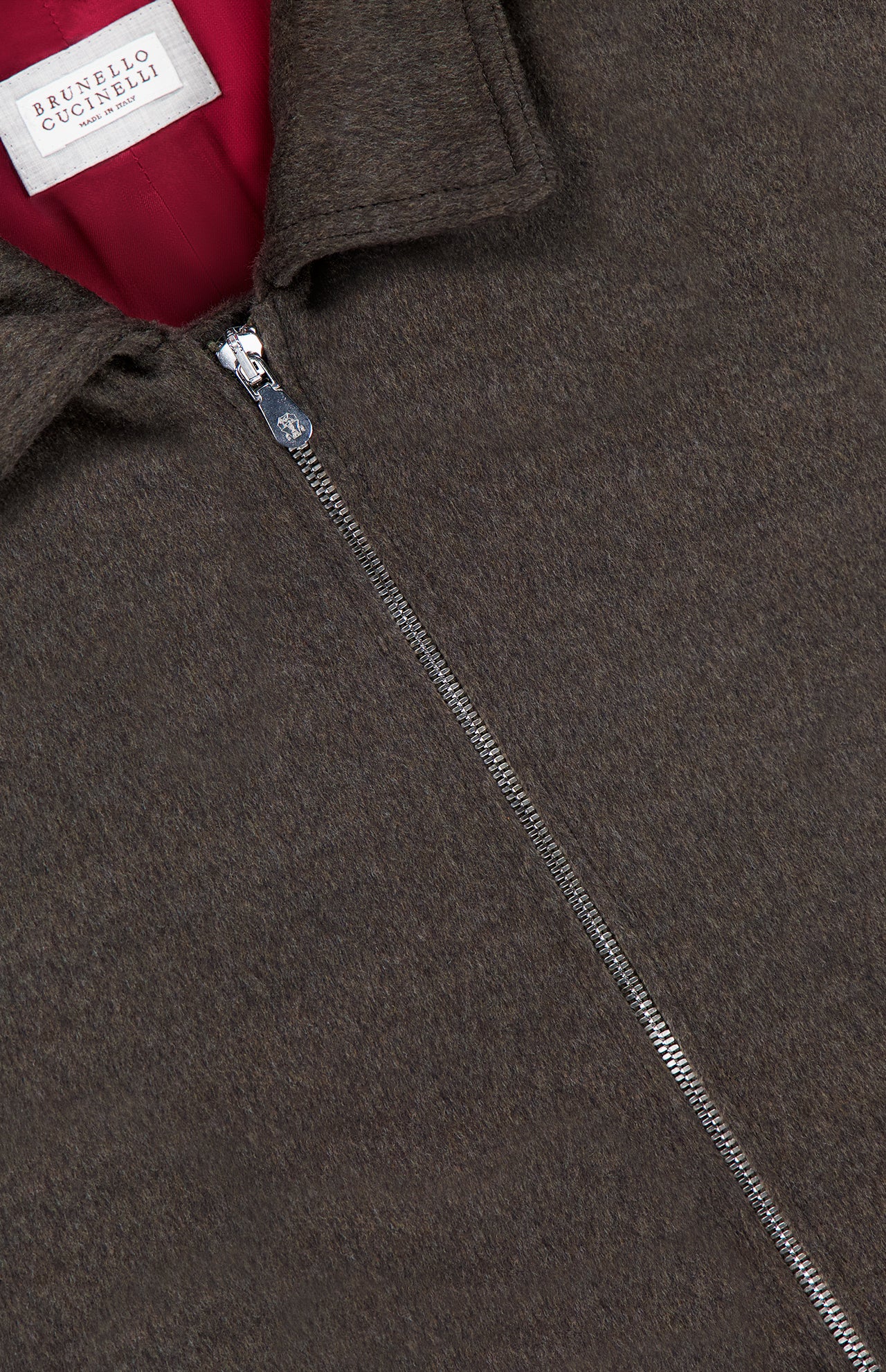 Close-up of the BRUNELLO CUCINELLI Wool Bomber Jacket in dark brown virgin wool, showcasing a prominent metal zipper, red inner lining, and a white BRUNELLO CUCINELLI label sewn near the collar.