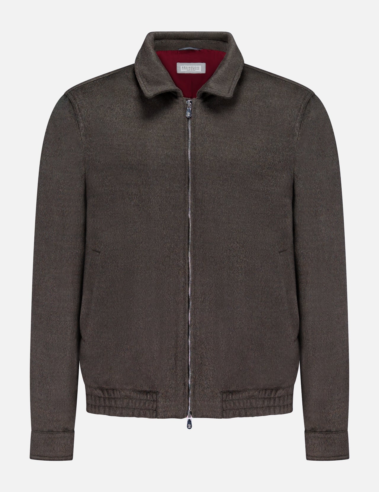 The BRUNELLO CUCINELLI Wool Bomber Jacket is showcased against a plain white background, featuring a dark brown hue with a zip-up front, classic collar, long sleeves, and an elasticized hem. Inspired by Brunello Cucinelli’s renowned craftsmanship, this virgin wool bomber is finished with a distinctive red label tag on the inside of the collar for an added touch of refinement.
