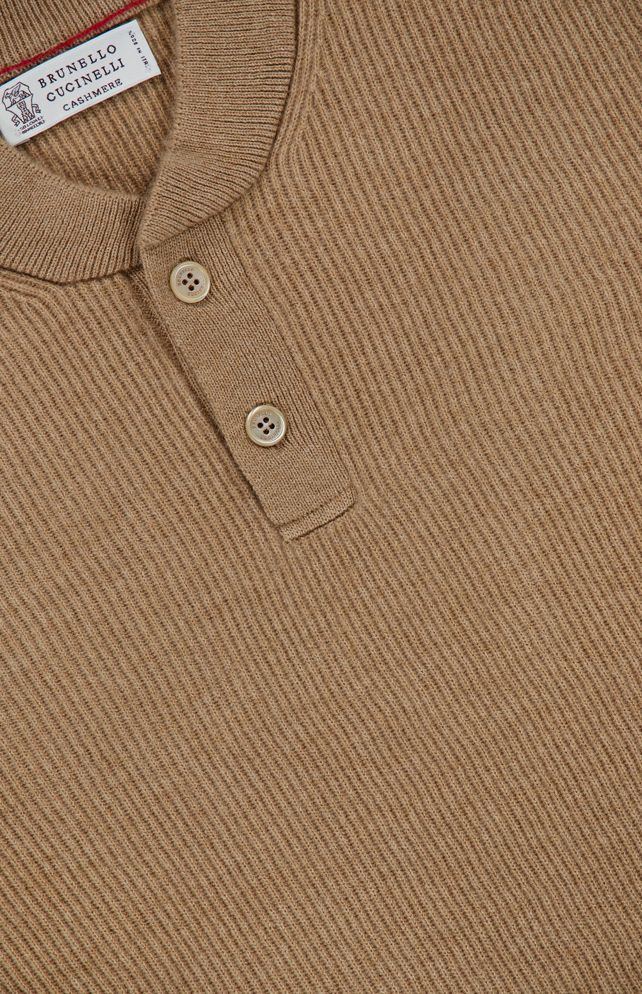 Close-up of the Cashmere Polo Sweater by BRUNELLO CUCINELLI in light brown ribbed knit, featuring a Henley collar with two beige buttons and a small BRUNELLO CUCINELLI label inside the collar.