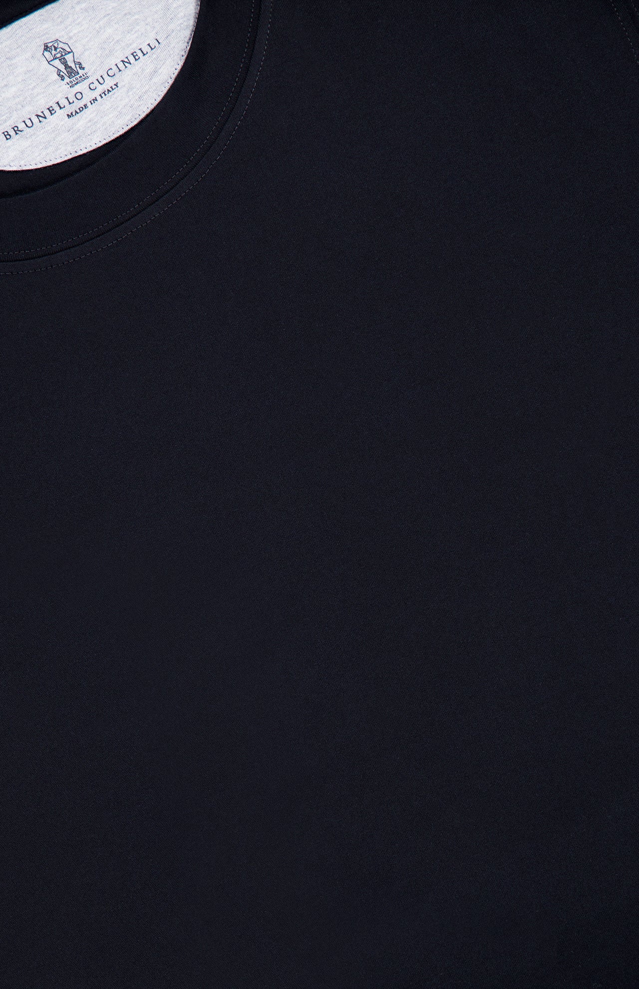 Close-up of the BRUNELLO CUCINELLI Cotton Crewneck T-Shirt in black, highlighting a portion of the collar and a white inner label with text, set against a plain background.