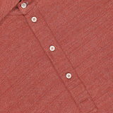 Close-up of a BRUNELLO CUCINELLI Cotton Linen Short Sleeve Polo Shirt in orange-red, featuring white buttons and a label reading MADE IN ITALY.