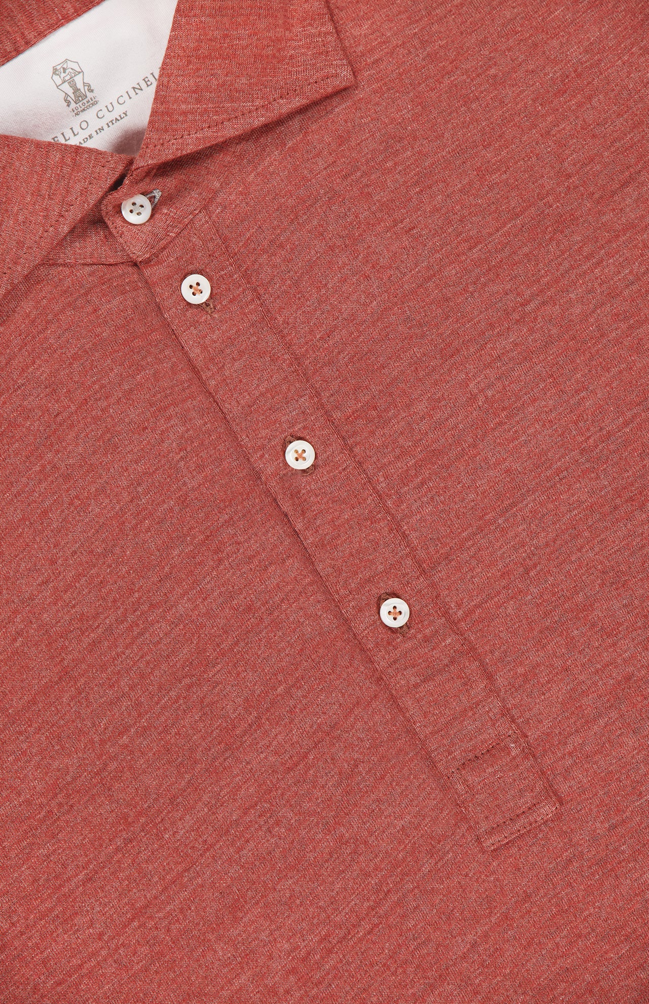 Close-up of a BRUNELLO CUCINELLI Cotton Linen Short Sleeve Polo Shirt in orange-red, featuring white buttons and a label reading MADE IN ITALY.