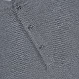 Close-up of a gray BRUNELLO CUCINELLI Cotton Long Sleeve Henley T-shirt featuring a textured waffle knit pattern and a partial button placket with two visible buttons near the collar.