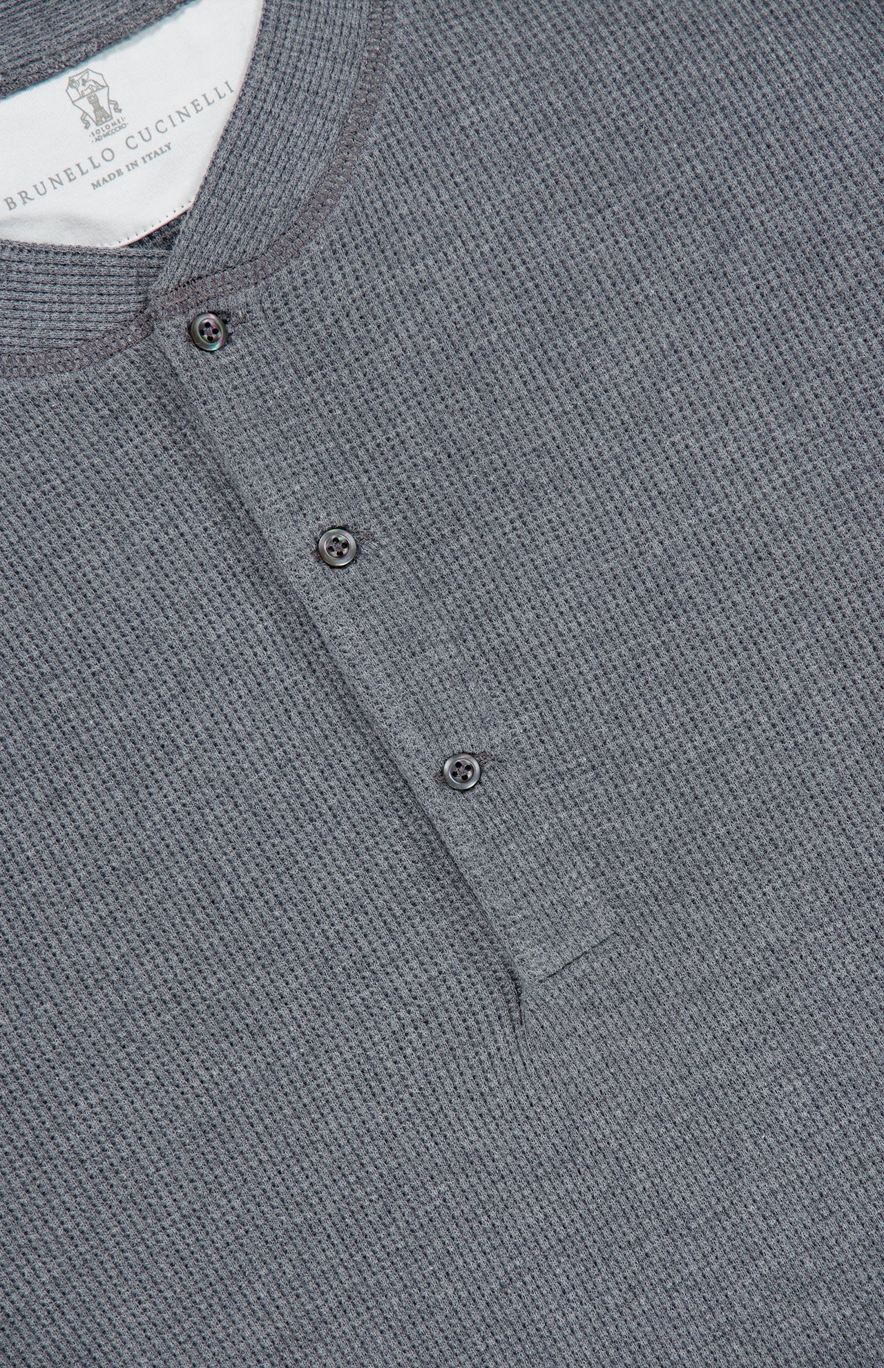 Close-up of a gray BRUNELLO CUCINELLI Cotton Long Sleeve Henley T-shirt featuring a textured waffle knit pattern and a partial button placket with two visible buttons near the collar.