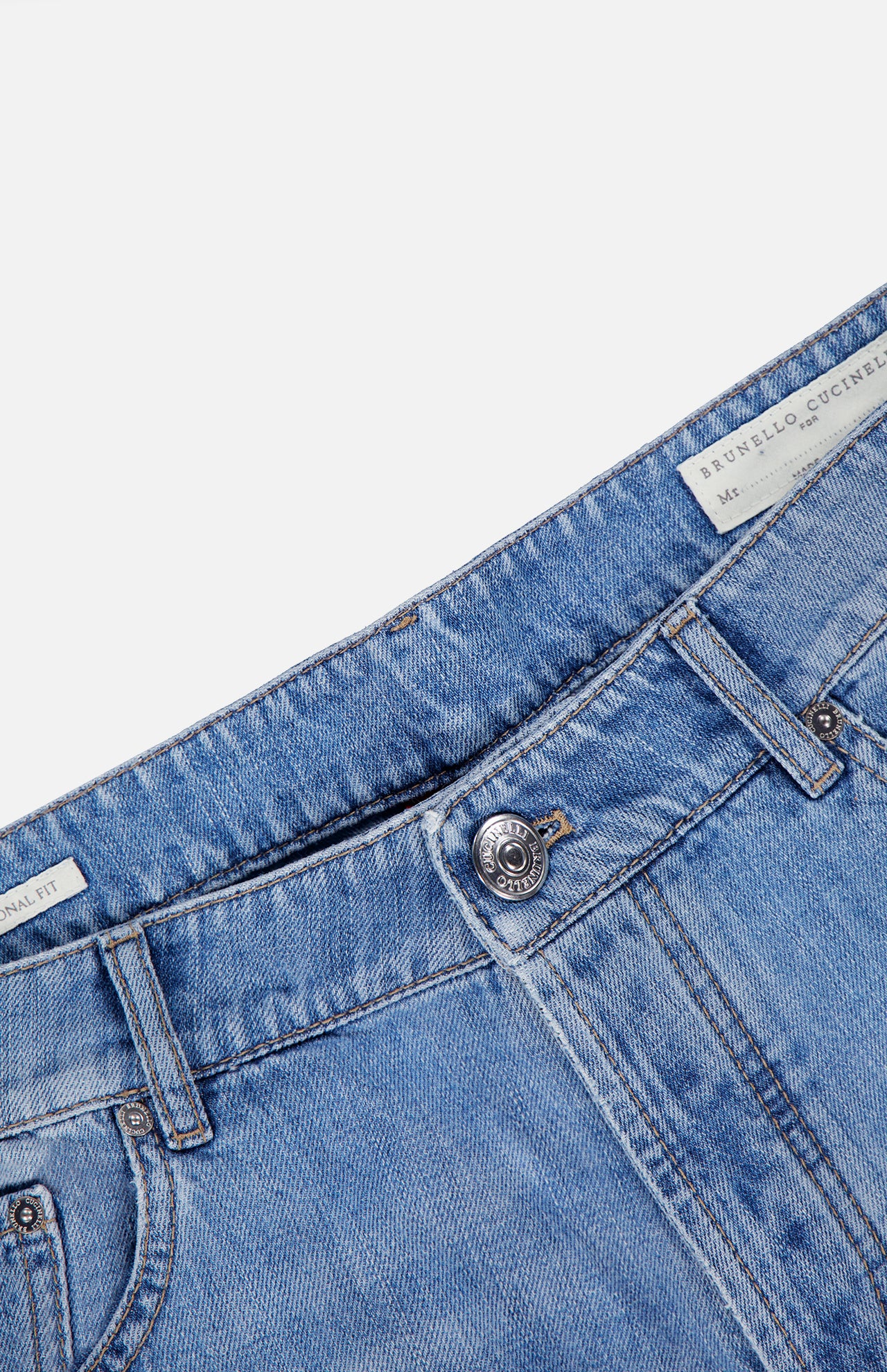 Close-up of the waist area of the Button Fly Denim Jeans by BRUNELLO CUCINELLI, crafted from premium light blue Italian denim with a visible metal button and belt loops. A white label inside the waistband displays the BRUNELLO CUCINELLI name, emphasizing the jeans' refined vintage treatment.