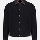 The BRUNELLO CUCINELLI Denim with Leather Collar Jacket features black denim, a dark brown leather collar, front pockets, and silver buttons—timeless retro style showcased against a plain white background.