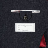 Close-up of the BRUNELLO CUCINELLI Double Breasted Suit Jacket interior in dark grey, highlighting a white brand label and a buttoned pocket, with burgundy lining crafted from luxurious virgin wool.