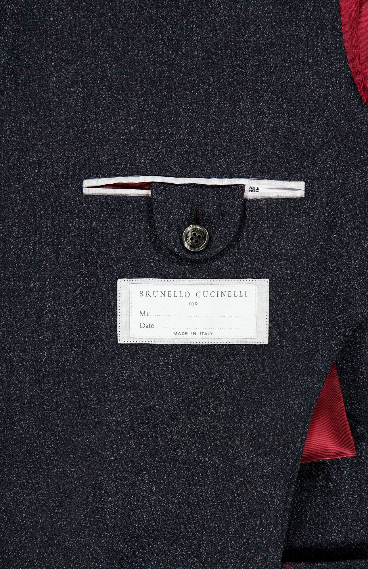Close-up of the BRUNELLO CUCINELLI Double Breasted Suit Jacket interior in dark grey, highlighting a white brand label and a buttoned pocket, with burgundy lining crafted from luxurious virgin wool.