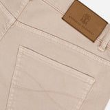 Close-up of the Button Fly Dyed Denim Pants in beige, expertly crafted from premium Italian denim by BRUNELLO CUCINELLI, highlighting the back pocket and waistband detailed with a brown leather patch embossed with the brand's logo.