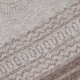 Close-up of a light beige BRUNELLO CUCINELLI Fair Isle Crewneck Sweater featuring intricate brown and cream geometric knit patterns across the chest. A portion of the BRUNELLO CUCINELLI label is visible near the collar.
